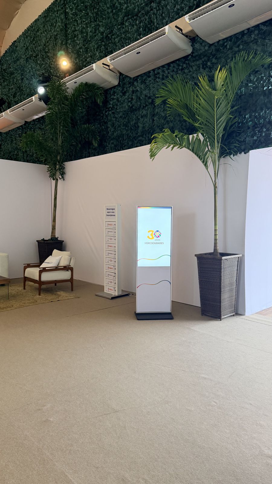 Totem touch screen instalado em lobby corporativo com jardim vertical